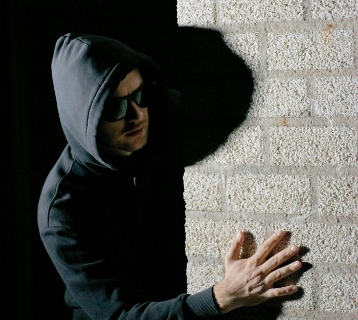 Man in a hooded jacket and sunglasses, leaning against a wall, illustrating historical misconceptions.