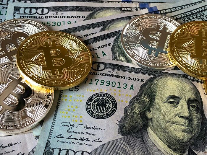 Cryptocurrency coins on hundred-dollar bills, illustrating financial scams.