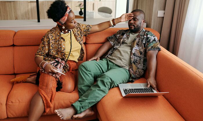 A couple sitting on an orange couch, looking stressed, possibly discussing wedding nightmares.