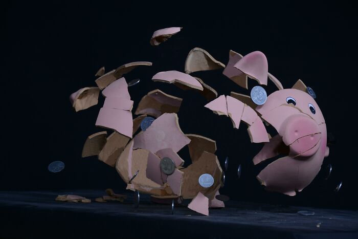 Shattered piggy bank with coins flying out, illustrating a historical turning point effect on finances.