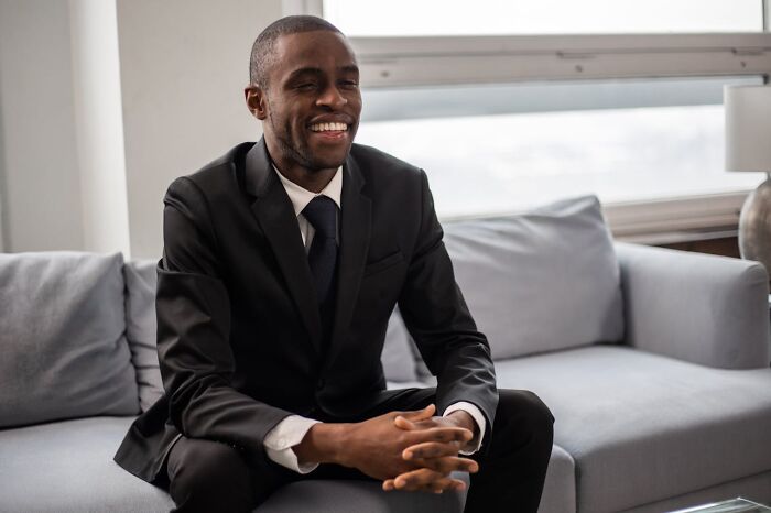 Smiling man in a suit on a couch, highlighting a positive job interview experience.