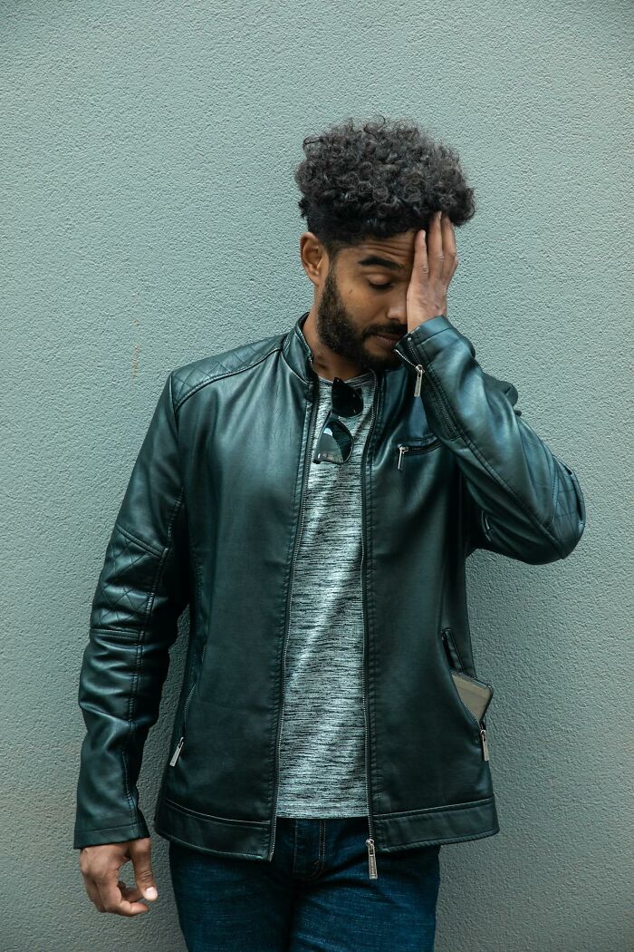 Man in a leather jacket looking frustrated with hand on face, symbolizing worst job bonus experience.
