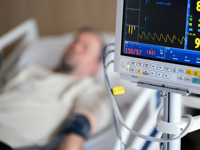 Patient in hospital bed with monitor displaying vital signs, highlighting healthcare worker insights on patient regrets.