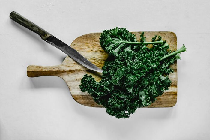Chopped kale on a cutting board with a knife, highlighting foods some find disgusting yet others purely enjoy.