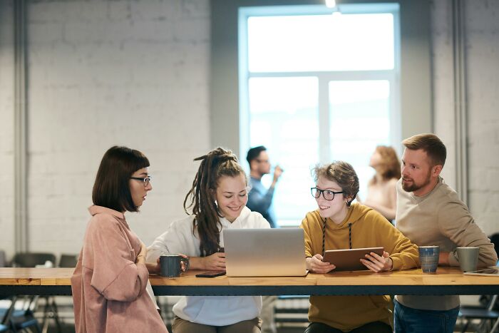A group of people discussing around a laptop and tablet, suggesting hidden intelligence in a collaborative workspace.