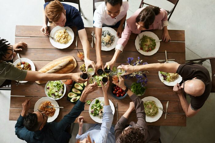 Group dining at a table, toasting with drinks.