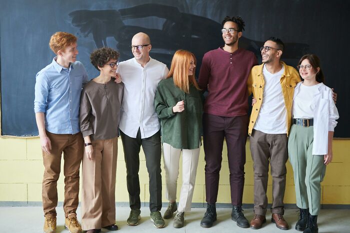 A diverse group of friends, smiling and standing in front of a blackboard, representing bisexual dating diversity.