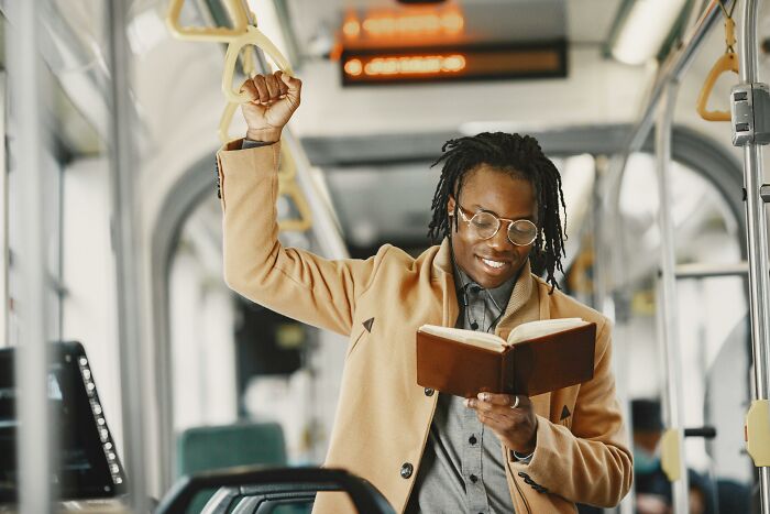 Person reading a book on public transport, showcasing a gradually disappeared habit.