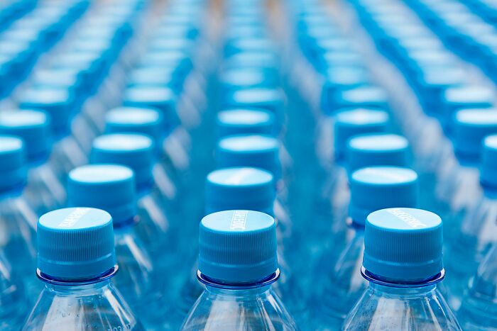 Rows of blue-capped water bottles arranged closely, concept related to sneaky scams.