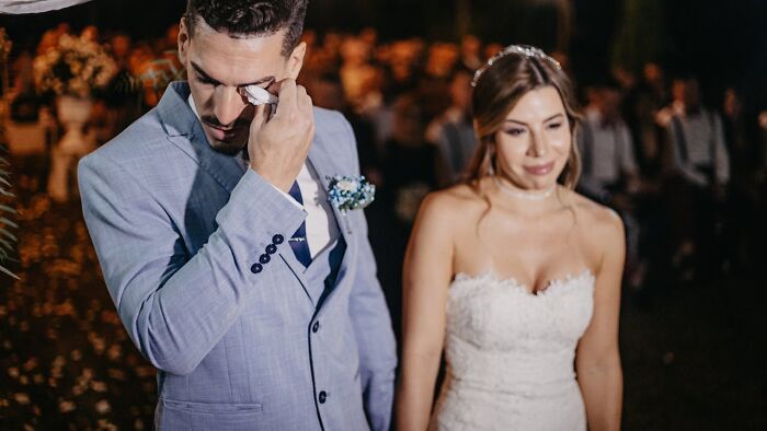 Groom wiping tears at a wedding, while standing beside a bride in a white dress, hinting at potential red flags.