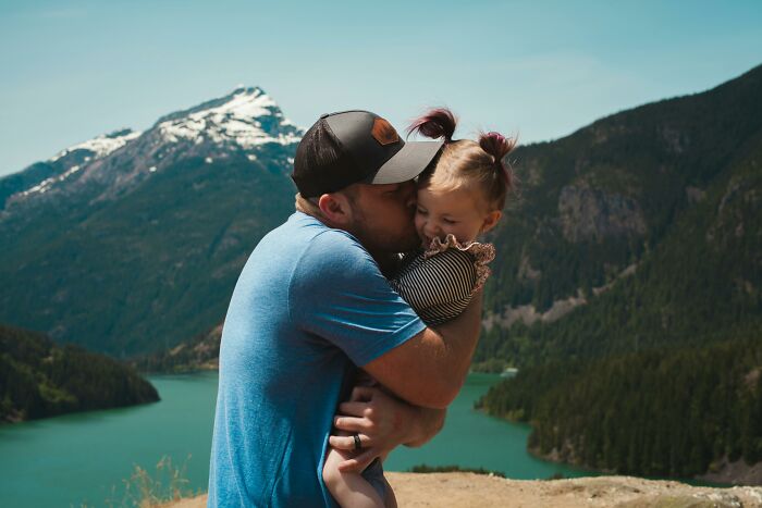 Man in a blue shirt hugging a child with scenic mountains in the background, capturing a moment related to patients' regrets.