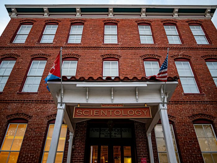 Red-brick Church of Scientology building with flags, symbolizing celebrity conspiracy notions.