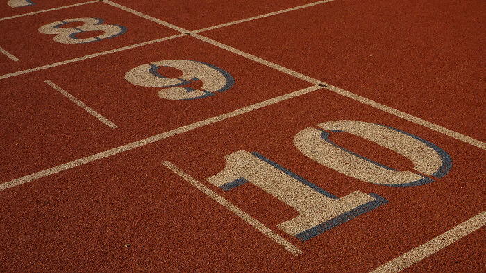 Running track lanes numbered 8, 9, 10 in focus, symbolizing competition and endurance.