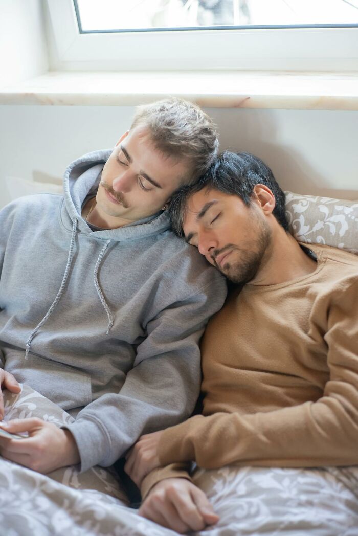Two men resting together peacefully, symbolizing comfort and support in a bedroom setting.