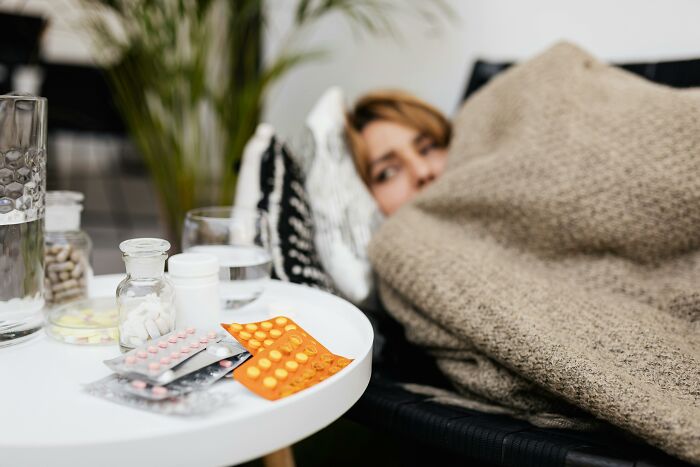 Person wrapped in a blanket on a couch, with medicine on the table; a wedding nightmare scenario.