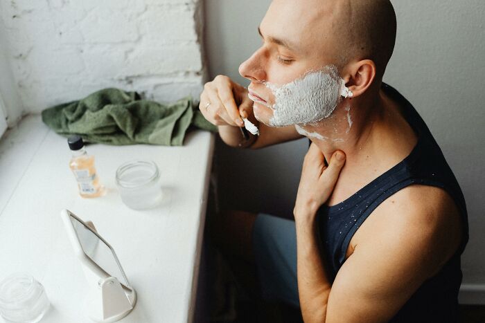 Man shaving with cream, using a mirror, as part of simple approaches to improve life.