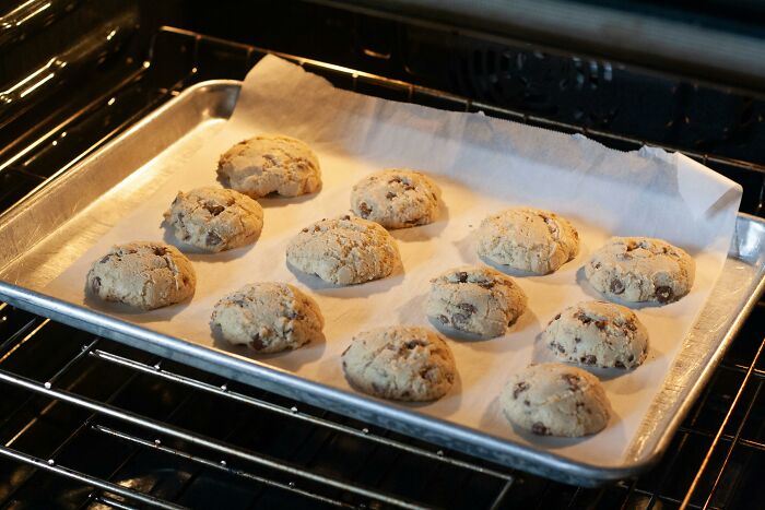 Cookies baking on a tray inside an oven, illustrating a commonly accepted baking misconception.