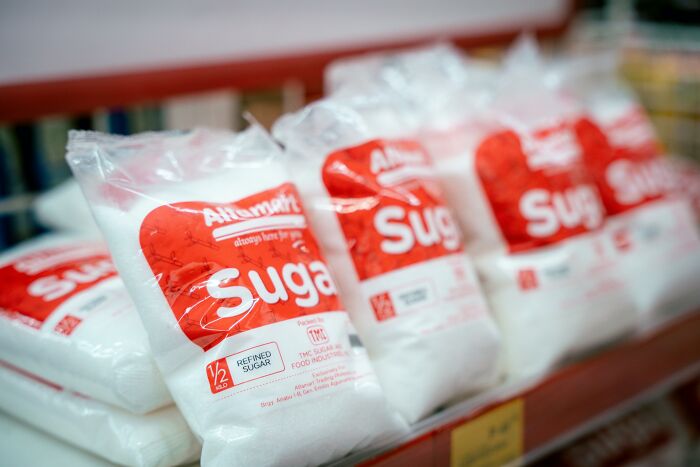 Bags of sugar on a store shelf, commonly used in making homemade bread.