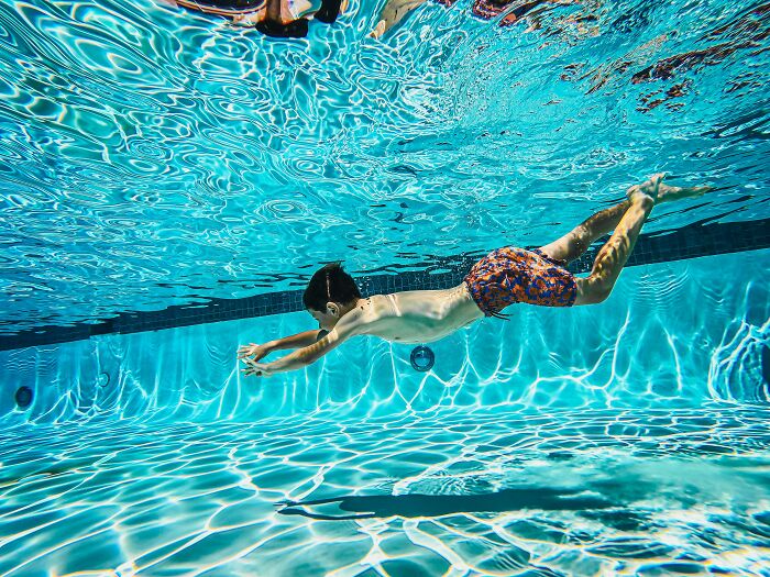 Child swimming underwater in a pool, illustrating common misconceptions about swimming techniques.