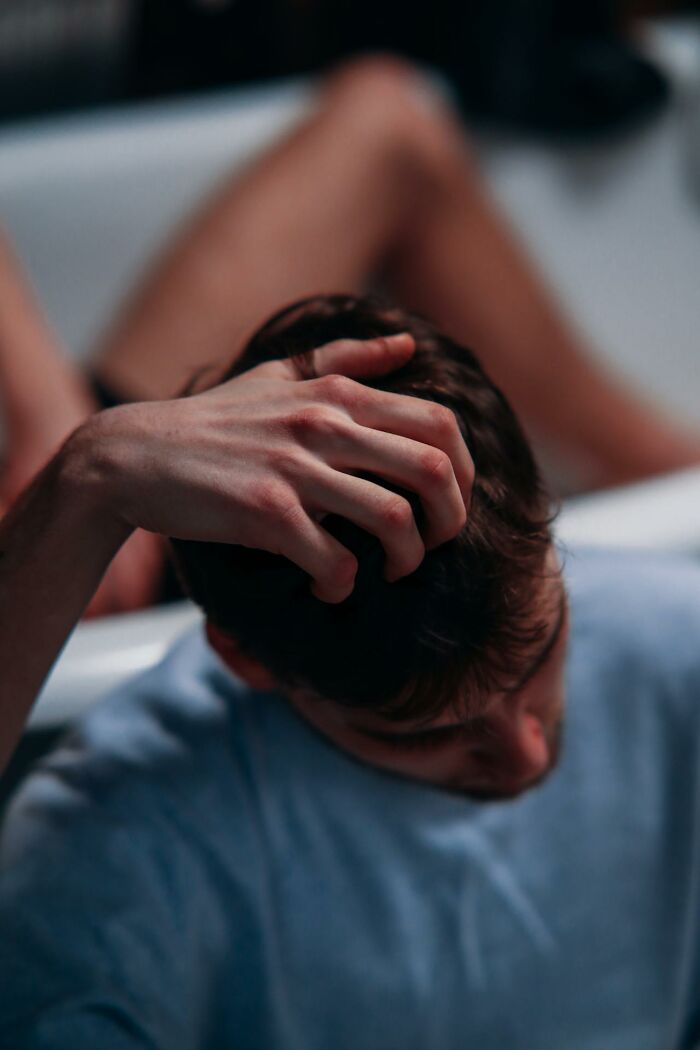 A person sitting in a bathtub, hand on head, reflecting on a scary true story.