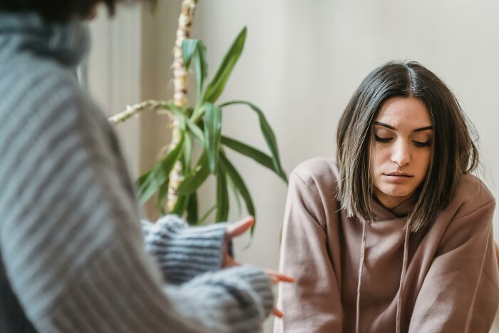 Woman in a brown hoodie appearing contemplative during a conversation, highlighting relationship challenges.
