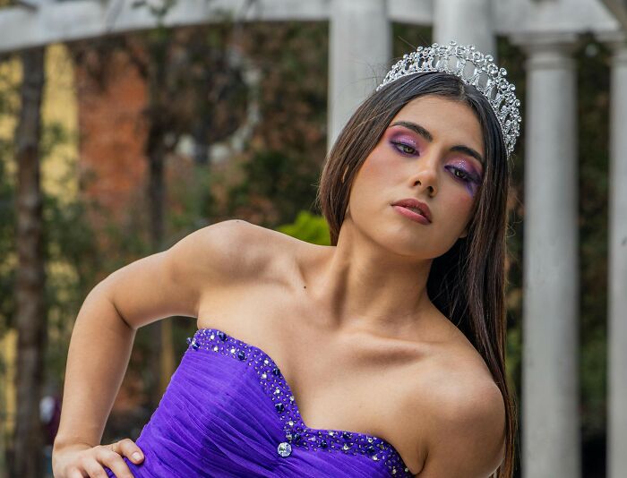 Young woman in a purple gown and tiara posing outdoors, representing what type to never date again.