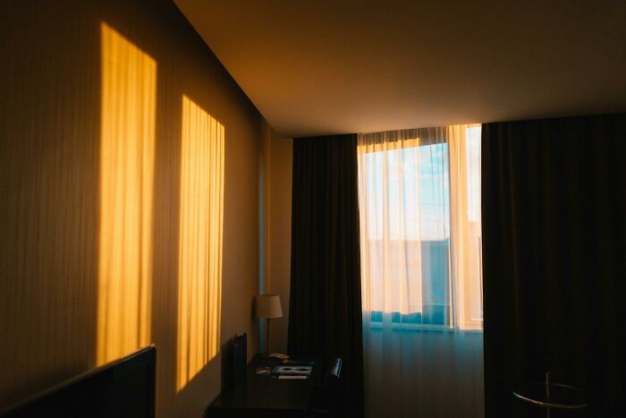 Sunlit room with curtains, casting shadows; a serene scene amidst tales of disruption.
