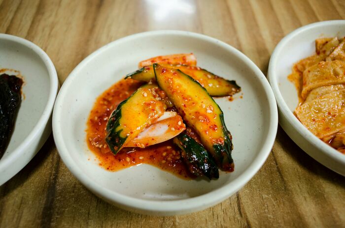 Pickled cucumber slices in spicy sauce on a white plate.