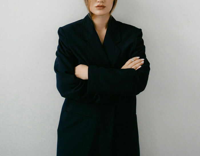 Woman in a dark blazer standing with arms crossed, representing moments of rejection.