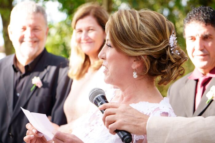 Wedding ceremony with a bride speaking into a microphone, surrounded by guests, highlighting wedding red flags.