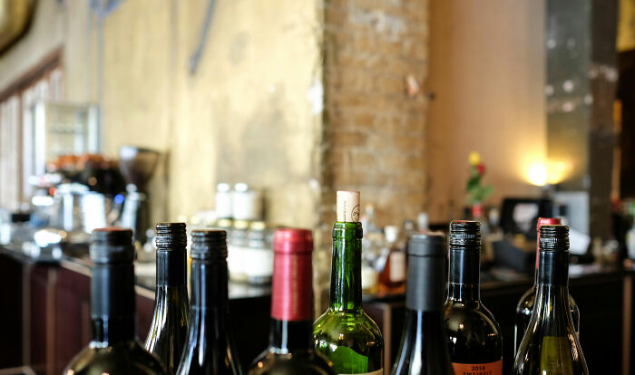 Bottles of wine on a bar counter with a rustic backdrop, conveying an informal setting related to unprofessional work attire.