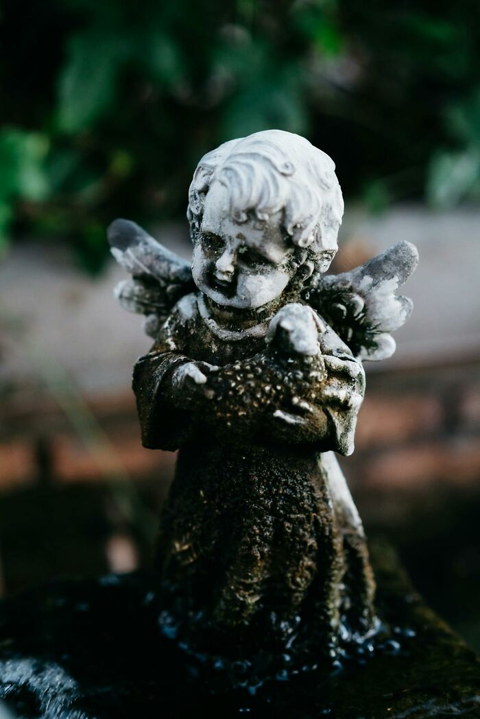 Weathered angel statue outdoors covered in moss.