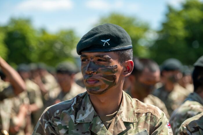 Soldier in camouflage face paint and uniform participates in harmless prank activities during training exercises.