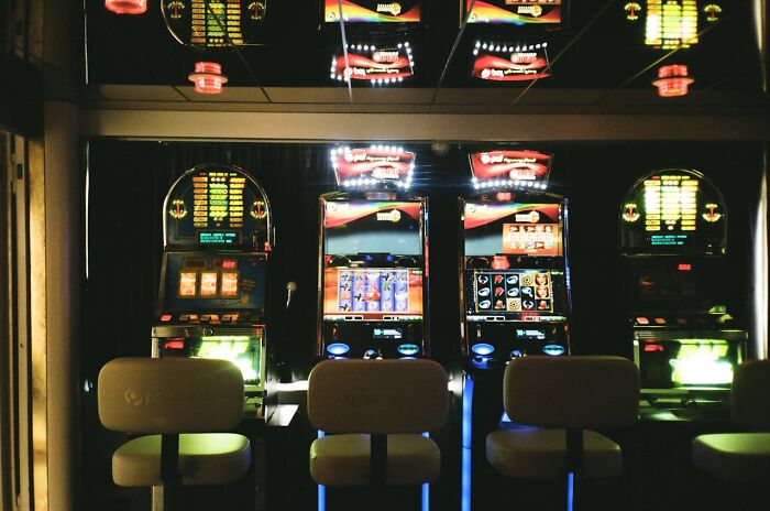 Slot machines in a dimly lit room, highlighting easy money opportunities and the allure of gambling winnings.