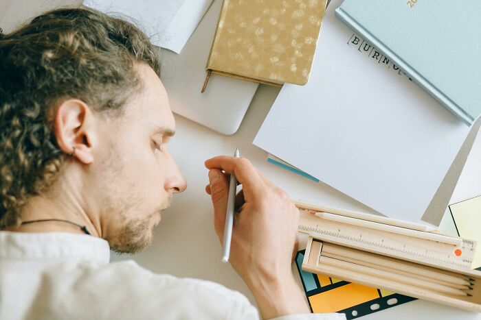 Person sleeping at desk surrounded by notebooks, symbolizing frustration with overused office expressions.