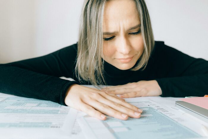 Woman concentrating on papers, appearing puzzled, related to language mastery and translation challenge.
