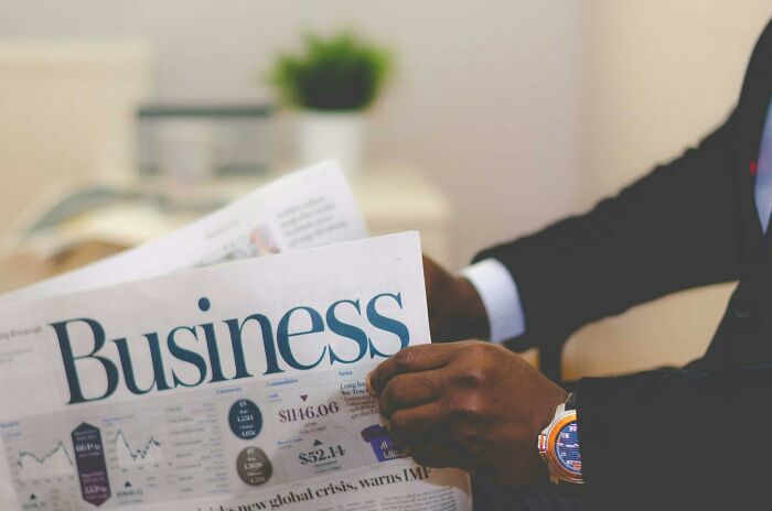 Man reading a business newspaper, highlighting the word "business" related to sneaky scams.