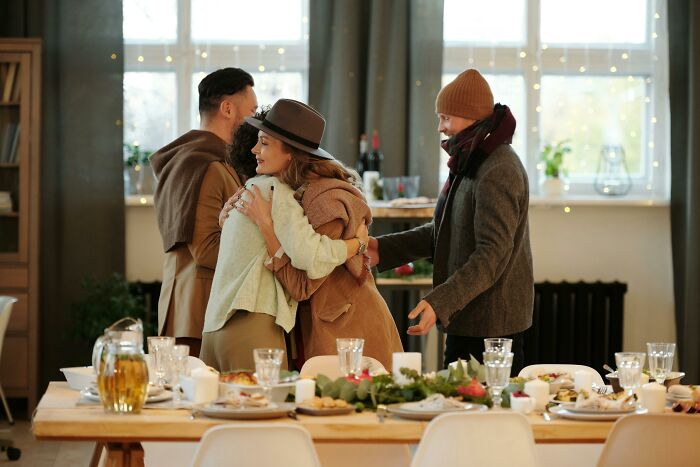 Adults embracing warmly at a festive table, sharing a moment that feels like being picked last, symbolizing inclusivity.