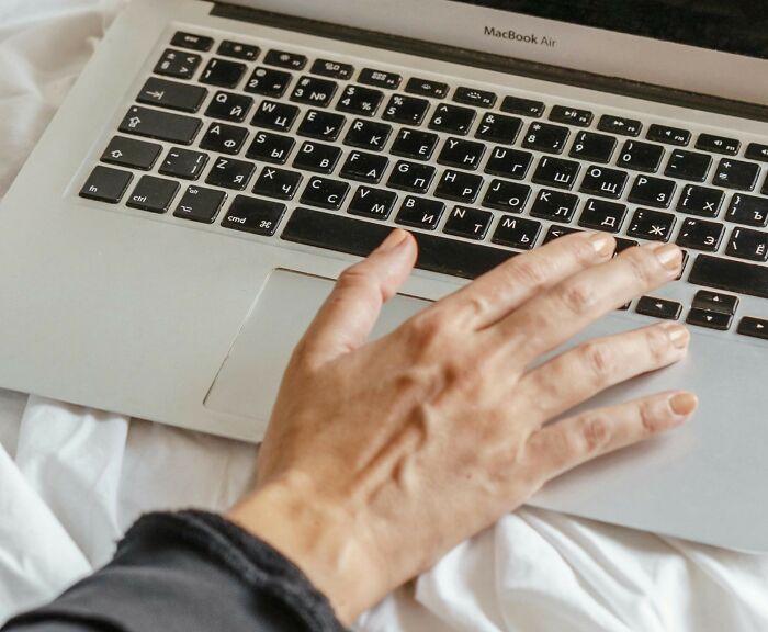 Hand on a laptop keyboard, typing about celebrity conspiracy theories.