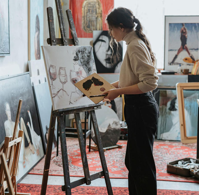 Woman painting in an art studio with various artworks around. Woman painting in an art studio with various artworks around.