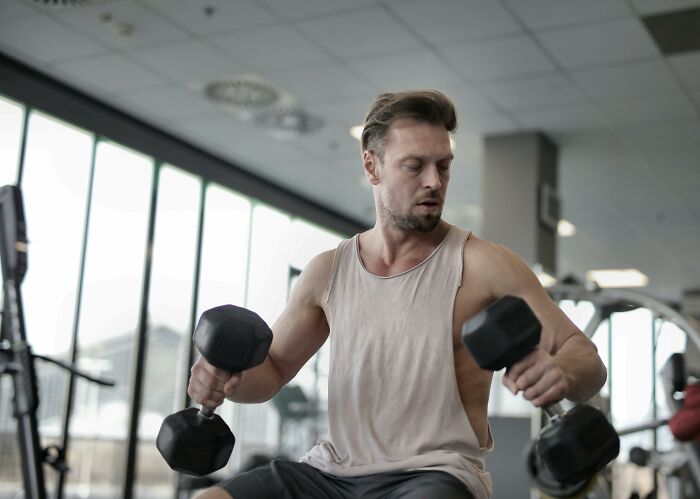 Man lifting dumbbells at the gym, focusing on his workout, representing fitness and strength.