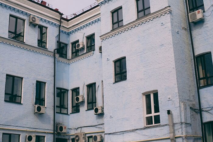 Old blue brick building exterior with multiple windows and air conditioning units.