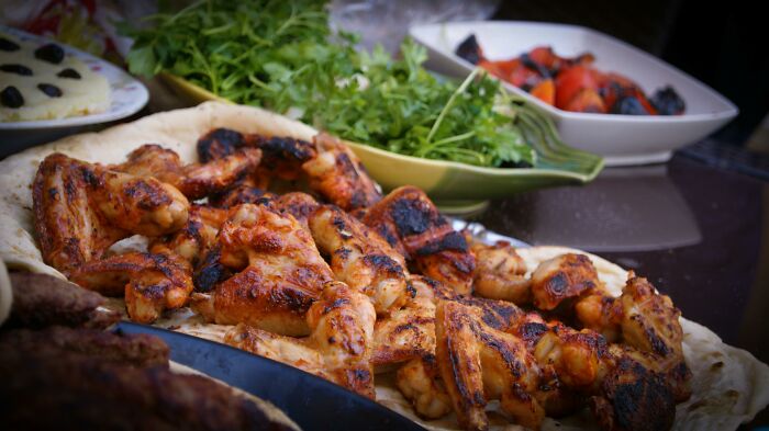 Grilled chicken wings on a platter, surrounded by fresh greens and roasted vegetables, evoking heartfelt compliments.