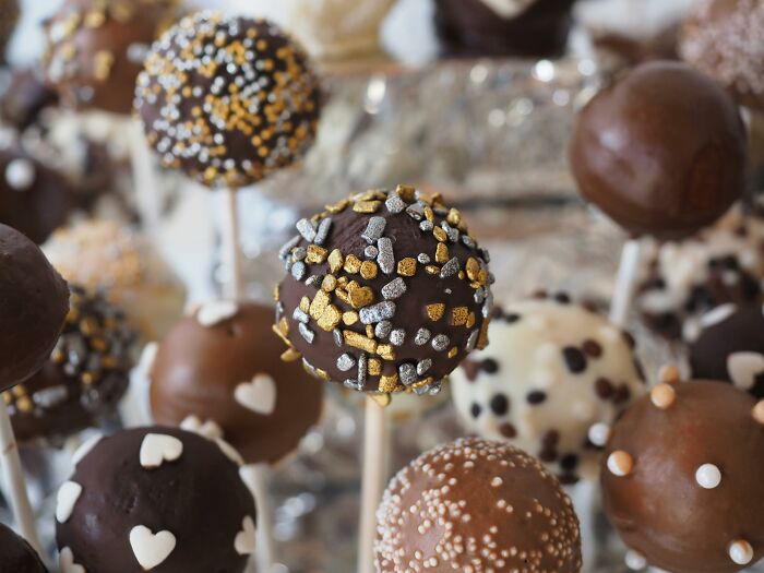 Chocolate cake pops decorated with various sprinkles, a food some might find unappealing despite its global popularity.