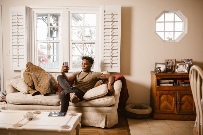 Man relaxing on a sofa, taking a selfie, associated with easy money-making stories like eating competitions.