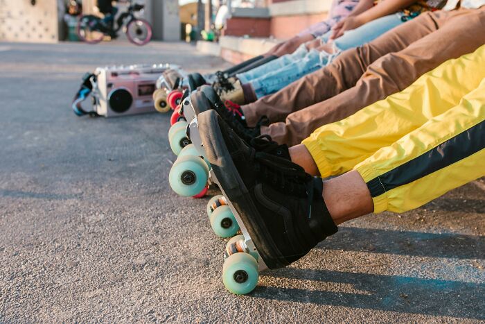 Roller skaters lined up outdoors, showcasing colorful styles. Creepiest women's stories in the backdrop.