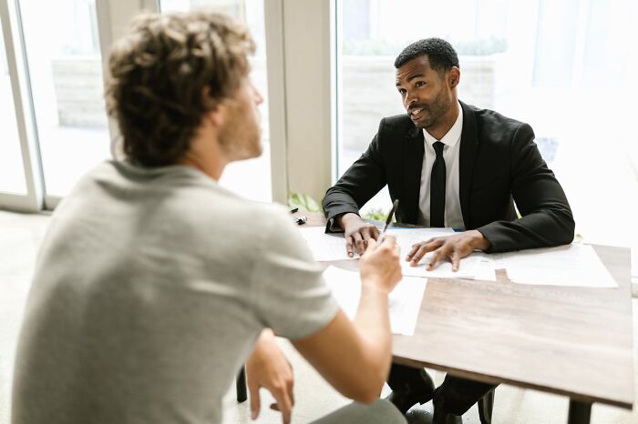Man in a suit conducting a job interview with a casually dressed candidate, illustrating a challenging job interview scenario.