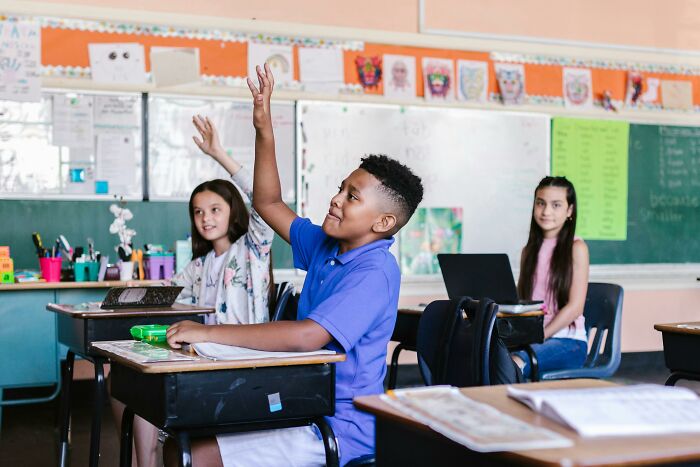 Students in a classroom raising hands, eager to answer historical facts taught by school teachers.