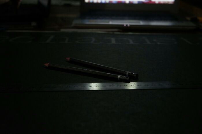 Two pencils on a dark surface next to a ruler, highlighting unusual measurement comparisons.