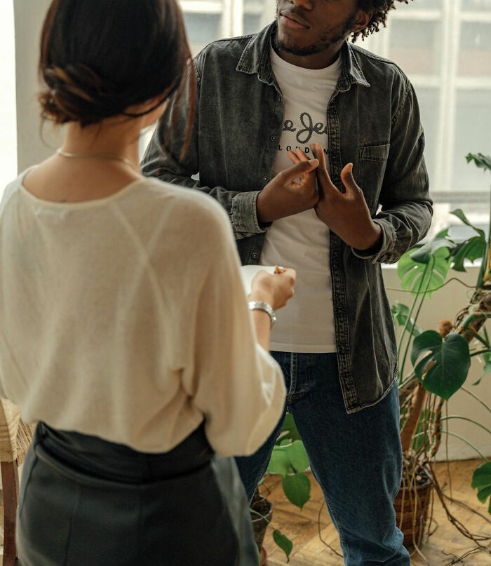 Man rejecting woman in conversation, wearing casual outfits, surrounded by plants, illustrating relationship dynamics.